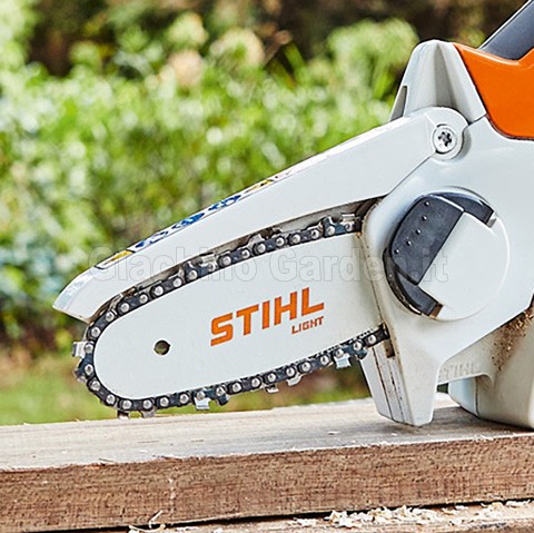 Dettaglio della catena e barra STIHL Light del potatore GTA 26 poggiato su un asse di legno in giardino
