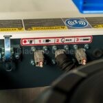 Dettaglio del pannello connessioni ausiliarie e adesivi di sicurezza del robot Barbieri X ROT 70 EVO, con prese numerate e icone di avvertenza
