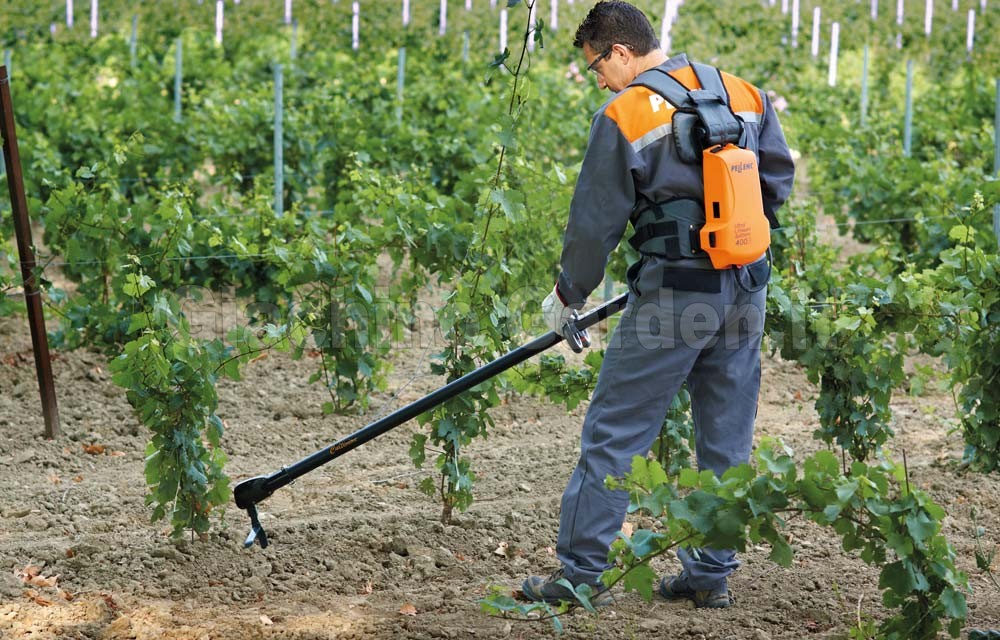Operatore esegue il diserbo meccanico interfilare tra i filari di un vigneto con la zappatrice elettrica Pellenc Cultivion.
