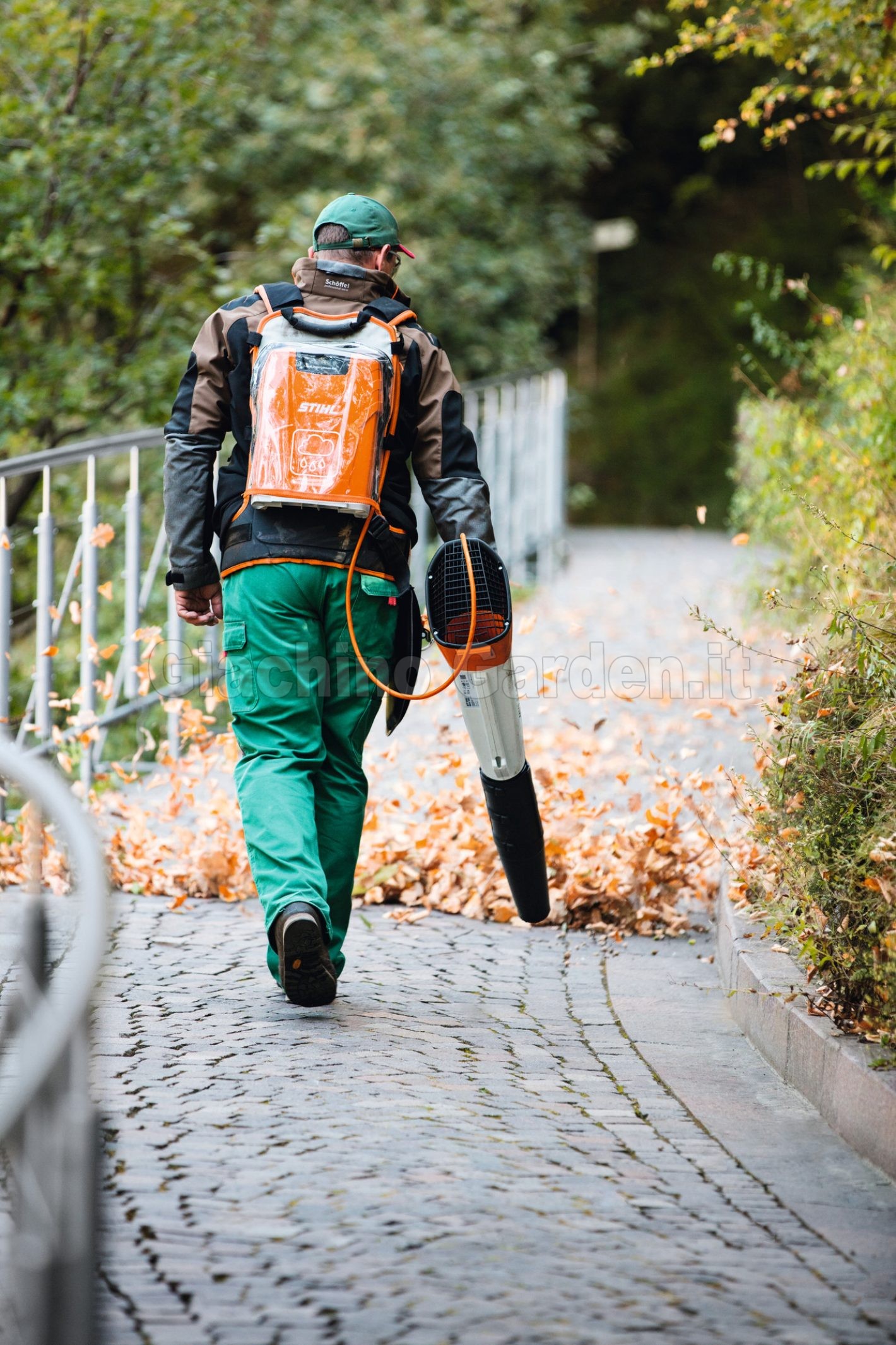 Giardiniere con soffiatore a batteria STIHL BGA 100 mentre pulisce un sentiero dalle foglie secche