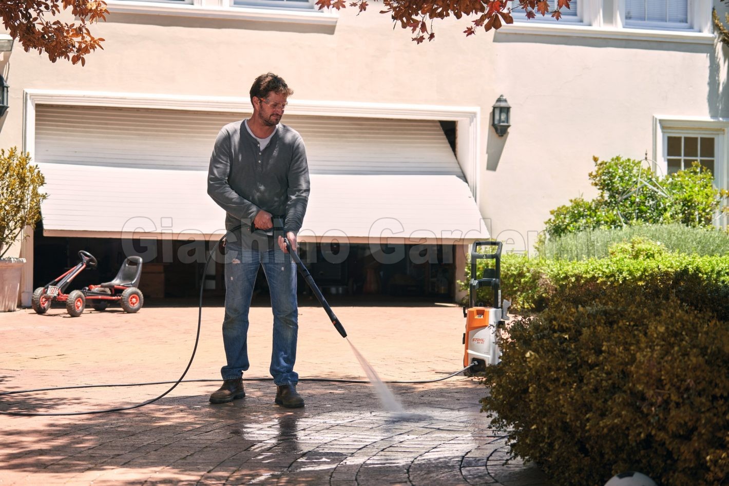 Utilizzo domestico dell'idropulitrice STIHL RE 90 per il lavaggio e la pulizia del pavimento esterno in un vialetto.