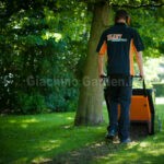 Giardiniere professionista con divisa Eliet mentre utilizza la macchina rigeneratrice prato DZC 600 in un parco.